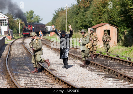 I soldati sulle linee ferroviarie che partecipano in WWII ri emanazione di cattura di una stazione ferroviaria Foto Stock