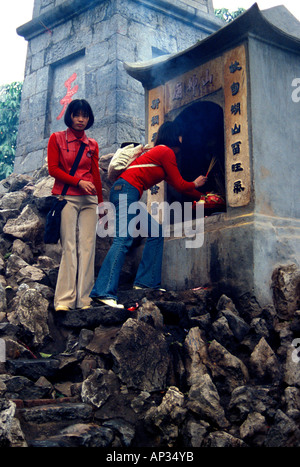 Due giovani donne vietnamite che illuminano i bastoni di incenso al tempio buddista/santuario della pagoda, Hanoi, Vietnam Foto Stock