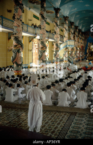 Discepoli di Caodaist, seduti durante la cerimonia da colonne colorate, Tempio di Cao dai, Tay Ninh, Vietnam Foto Stock