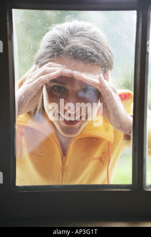 Donna che guarda attraverso una finestra in alp lodge, Heiligenblut, Parco Nazionale degli Hohe Tauern, Carinzia, Austria Foto Stock