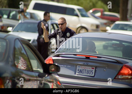 Tenendo un fischio nella sua bocca un poliziotto dirige il pesante traffico vacanze in Laguna Beach California Foto Stock