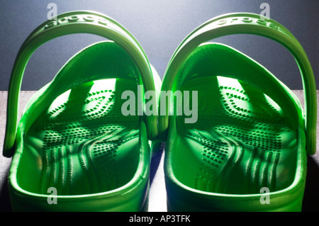 Una coppia di Bright Green Crocs zoccoli con luce che risplende attraverso il modello di fori della tomaia Foto Stock