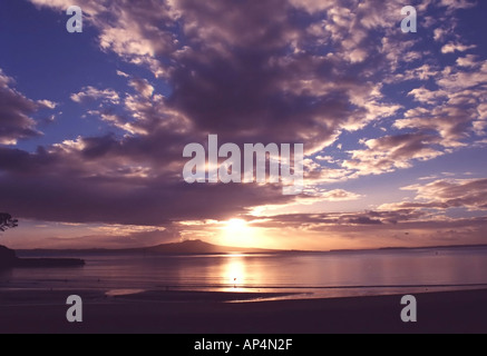 Il sole sorge da dietro Rangitoto isola al largo di Auckland in Nuova Zelanda Foto Stock