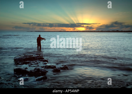 Il pescatore pesca lure a Ogmore estuario del fiume Ewenny Tramonto Foto Stock