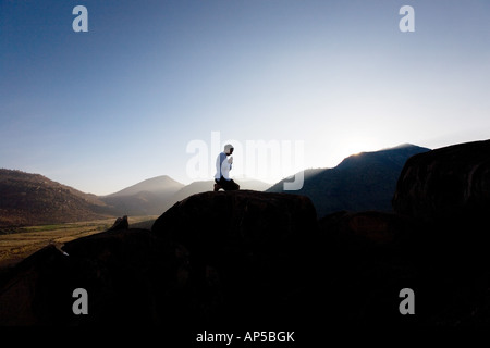 Silhouette di un uomo che prega su un Indiano mountain top di sunrise Foto Stock