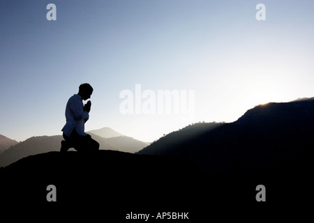 Silhouette di un uomo che prega su un Indiano mountain top di sunrise Foto Stock