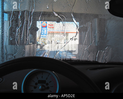 Flussi di acqua che scorre verso il basso il parabrezza della vettura andando attraverso il lavaggio automatico facility Foto Stock