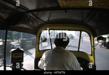 Un motore di Bajaj rickshaw e conducente visto dall'interno del cappuccio su una strada di Pune in India Foto Stock