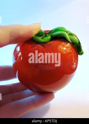 Una mano che tiene un vetro rosso pomodoro Foto Stock