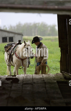 Cowboy a cavallo sotto la pioggia in Judith Gap Montana (MR) Foto Stock