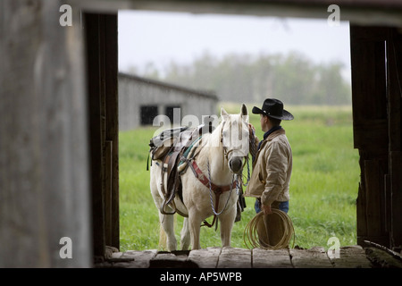 Cowboy a cavallo sotto la pioggia in Judith Gap Montana (MR) Foto Stock