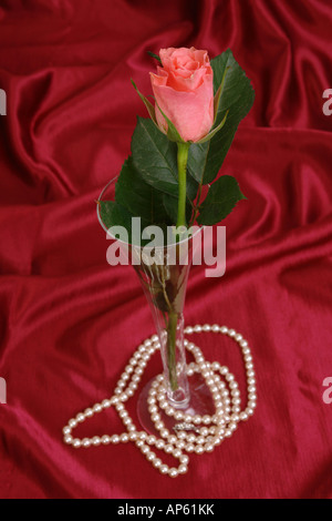 Filo di Perle e rosa rosa in vetro su red satine tessuto Foto Stock