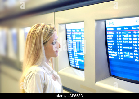 Giovane imprenditrice visualizzazione orario dei voli informazioni sui monitor all'aeroporto Foto Stock