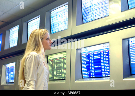 Giovane imprenditrice visualizzazione orario dei voli informazioni sui monitor all'aeroporto Foto Stock