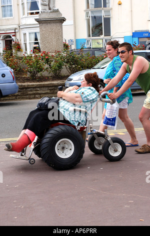 Un sovrappeso disabilitato femmina è spinto dal suo marito in una sedia a rotelle convertito per le persone obese Foto Stock