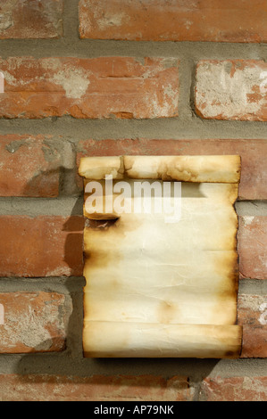 Vecchia pergamena con bordi bruciato sul muro di mattoni Foto Stock