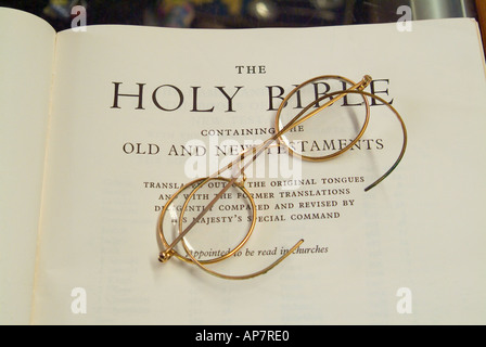 Coppia di oro occhiali bordati di nella pagina del titolo di una vecchia Bibbia Foto Stock