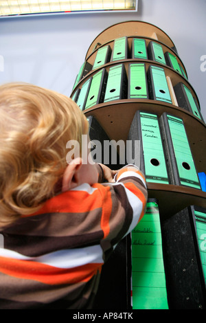 Piccolo Ragazzo davanti a una cartella rack di stoccaggio in ufficio Foto Stock