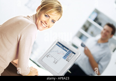 Ritratto di una giovane donna che lavorano su un computer con un giovane uomo in piedi in background Foto Stock
