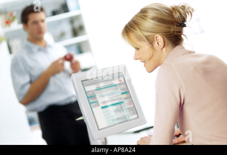 Il profilo laterale di una giovane donna che lavorano su un computer di un giovane uomo in piedi in background Foto Stock