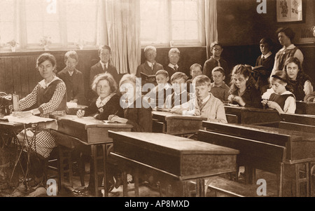 Bambini in età junior in classe a scuola primaria, con un insegnante che usa una macchina da cucire, lezione di lavoro all'ago, Cambridge, Inghilterra, UK - circa 1918 Foto Stock