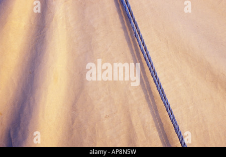 Dettaglio di colore bianco in plastica o nylon telone foglio in una luce calda bisecati mediante due parallele blu pallido funi in nylon Foto Stock