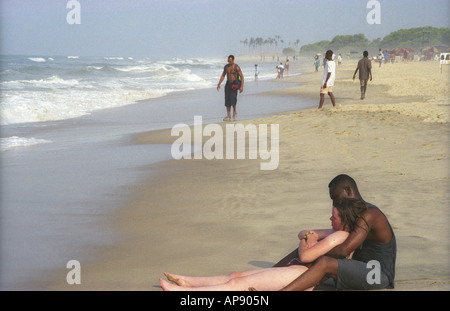 Giovani razza mista paio di neri africani e uomo bianco donna caucasica lounge e abbracciare sulla spiaggia Labadi Accra Ashanti in Ghana Foto Stock