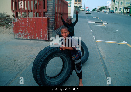 Nero ragazzi giocare con pneumatici in strada Swakopmund Namibia 2000 Foto Stock