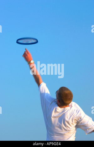 Un adolescente di salti e si allunga per la cattura di un flying frisbee. Foto Stock
