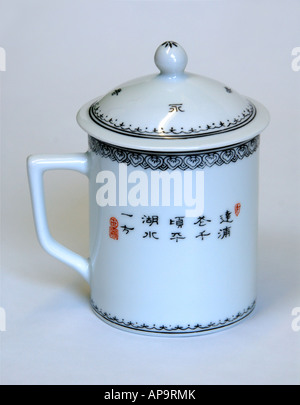 In ceramica cinese tazza da tè con coperchio, di colore bianco con caratteri scritti in nero e arancio. Foto Stock