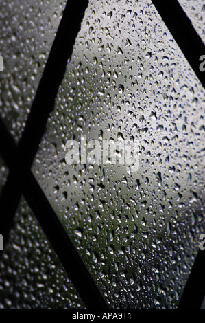 Gocce di pioggia su un vetro di finestra con luci con piombo Foto Stock