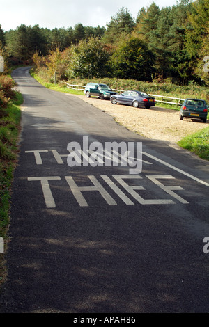 Pensare al ladro dipinta su una strada di campagna vicino parcheggio auto Dorset Southern England Regno Unito Foto Stock