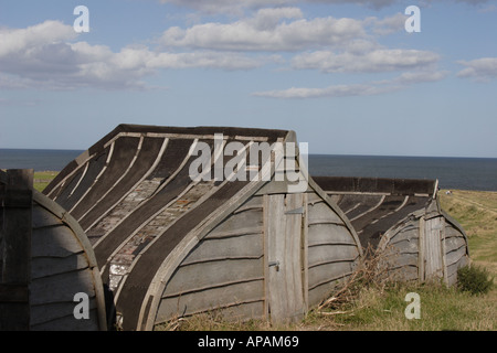 Barche capovolta utilizzati come magazzini di stoccaggio su Lindisfarne Foto Stock