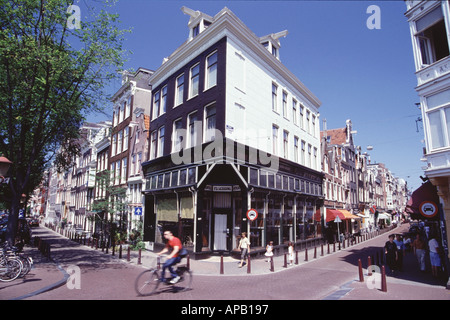 Streetcorner nel quartiere degli antiquari di Amsterdam Paesi Bassi con un ciclista che passa attraverso il telaio Foto Stock