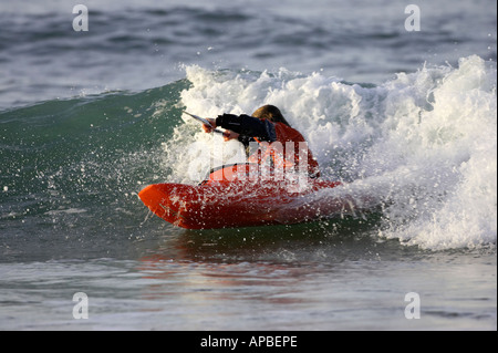 Kayaker maschio cavalca un onda nel mare di rocce bianche beach portrush County Antrim Irlanda del Nord Foto Stock