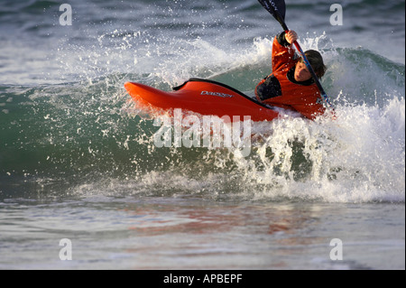 Kayaker maschio cavalca un onda nel mare di rocce bianche beach portrush County Antrim Irlanda del Nord Foto Stock