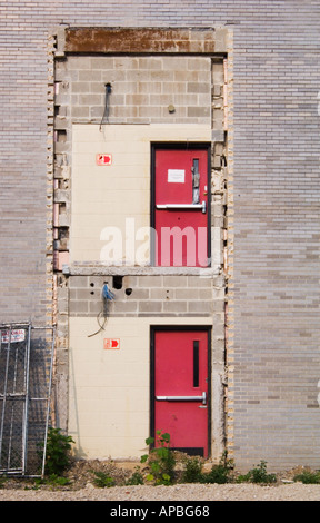 Mattone di Edificio industriale con due porte di rosso per nulla nel lato sulla parte superiore di ogni altro con questo modo alle insegne Foto Stock