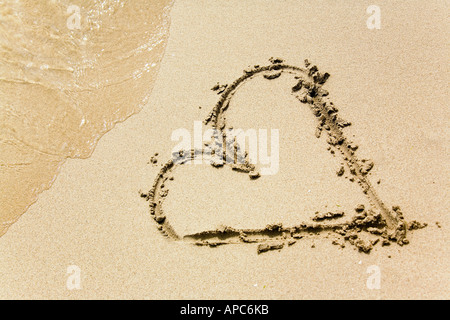 Un cuore disegnato nella sabbia di una spiaggia Foto Stock