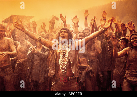 Persone su un open-air celebrando la pioggia dopo una giornata calda nella parte anteriore di un ragazzo in un nativo americano vestito. Festival StrangeNoise Foto Stock