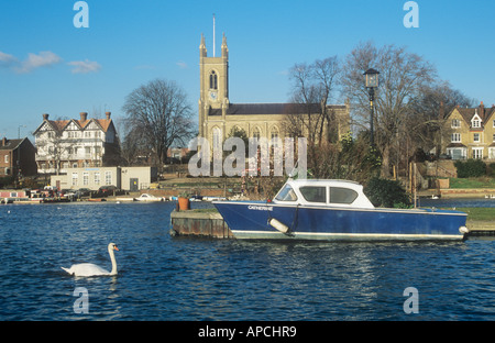 Swan e barca ormeggiata sul Fiume Tamigi, con la Chiesa di Hampton del Middlesex Banca, da West Molesey, Surrey, England, Regno Unito Foto Stock