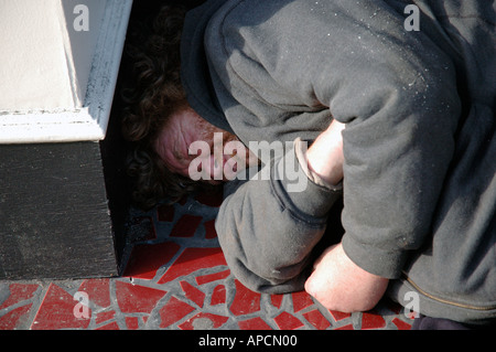 Senzatetto uomo addormentato in un portale in Soho di Londra. Foto Stock