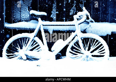 Una bicicletta con neve accanto a una recinzione. Foto Stock