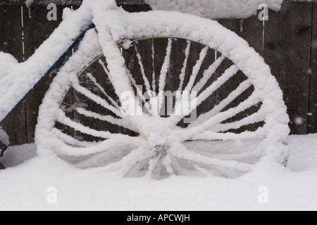 Una bicicletta con neve accanto a una recinzione. Foto Stock