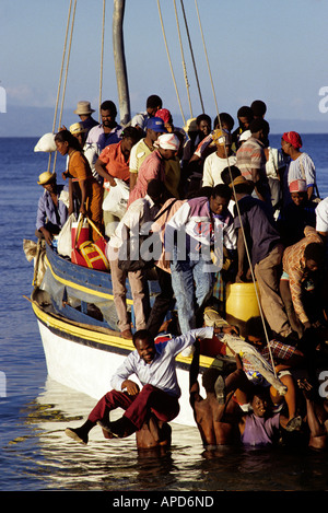 Haiti Saint Marc Facchini trasportano passeggeri e merci da sovraccarico dal traghetto Île de la Gonave presso sunrise Foto Stock