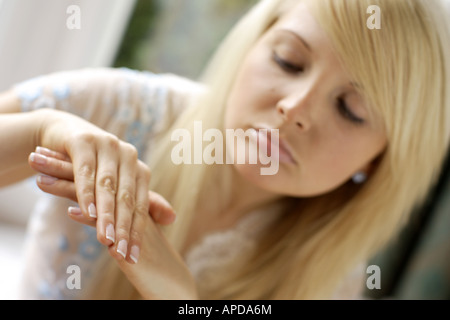 Donna che guarda le sue mani Foto Stock