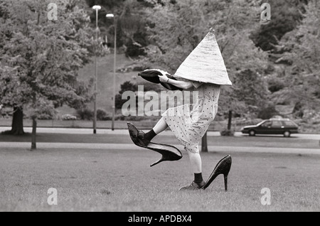 L'attrice larking circa sull'erba con i puntelli per alternativa commedia mostra che comportano enormi hat e scarpe. Foto Stock
