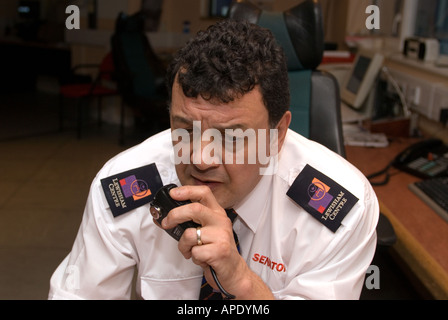 La guardia di sicurezza sul dovere di controllo TVCC parlando di camera su radio Lewisham Shopping Centre di Londra Foto Stock
