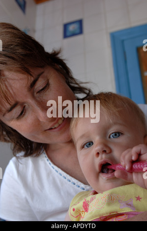 Una madre guarda la sua figlia di lavarsi i denti Foto Stock