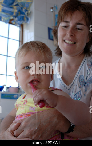 Una madre guarda la sua giovane figlia lavarsi i denti prima di andare a dormire Foto Stock