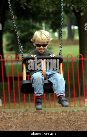 Serian età tre nel parco sulle altalene Foto Stock